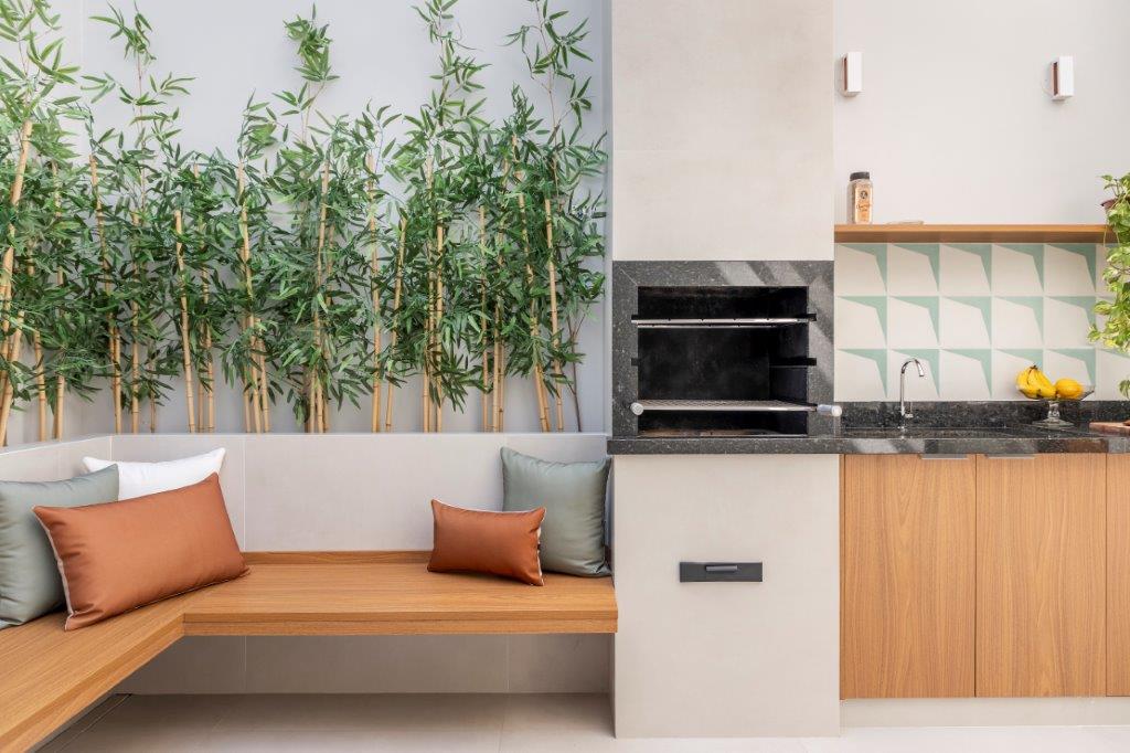 Casa de 146 m² ganha cozinha verde clara e área externa com churrasqueira. Projeto de Camila Bischoff. Na foto, área externa, jardim, parede de azulejos, bancada preta.