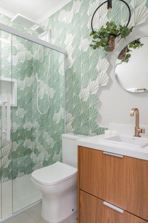 Casa de 146 m² ganha cozinha verde clara e área externa com churrasqueira. Projeto de Camila Bischoff. Na foto, banheiro, ladrilhos verdes, bancada branca, espelho redondo, metais dourados.