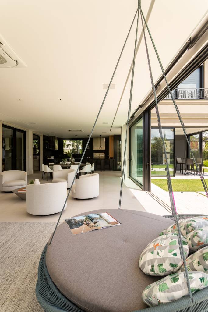 Casa de 900 m² tem jardim com jabuticabeira no living. Projeto de Patricia Penna Arquitetura & Design. Na foto, sala de estar com cadeira de balanço