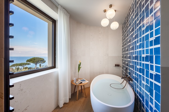Hotel na Itália tem inspiração mediterrânea e vistas encantadoras. Projeto do estúdio Spagnulo&Partners. Na foto, banheiro com banheira oval e revestimento em azul.