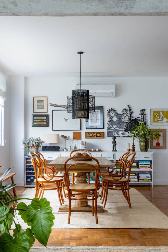 Memórias e histórias de viagem permeiam apê de 170 m². Projeto de Camila Niskier e Noa Arquitetos. Na foto, sala, mesa de jantar, luminária, gallery wall.
