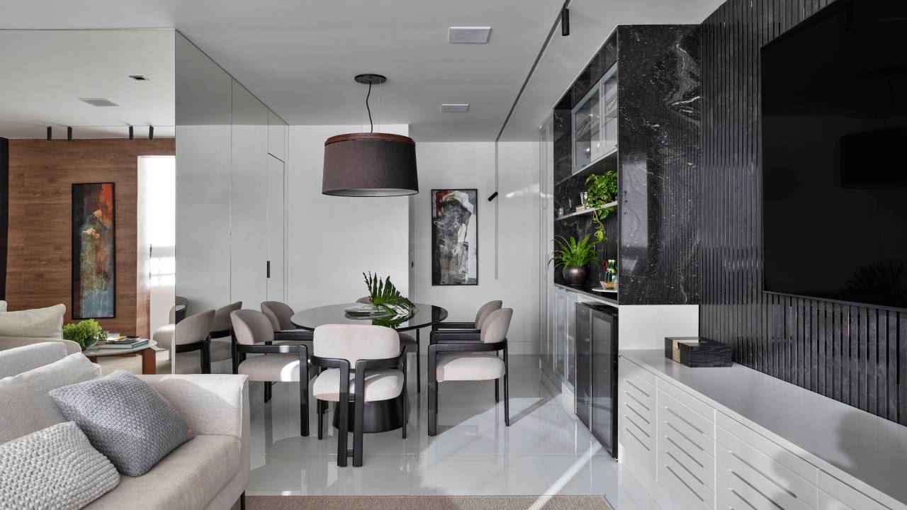 Com paleta ancorada no preto, apê tem painel ripado e piso de porcelanato. Projeto de Rebeca de França. Na foto, sala, espelho, painel ripado preto.