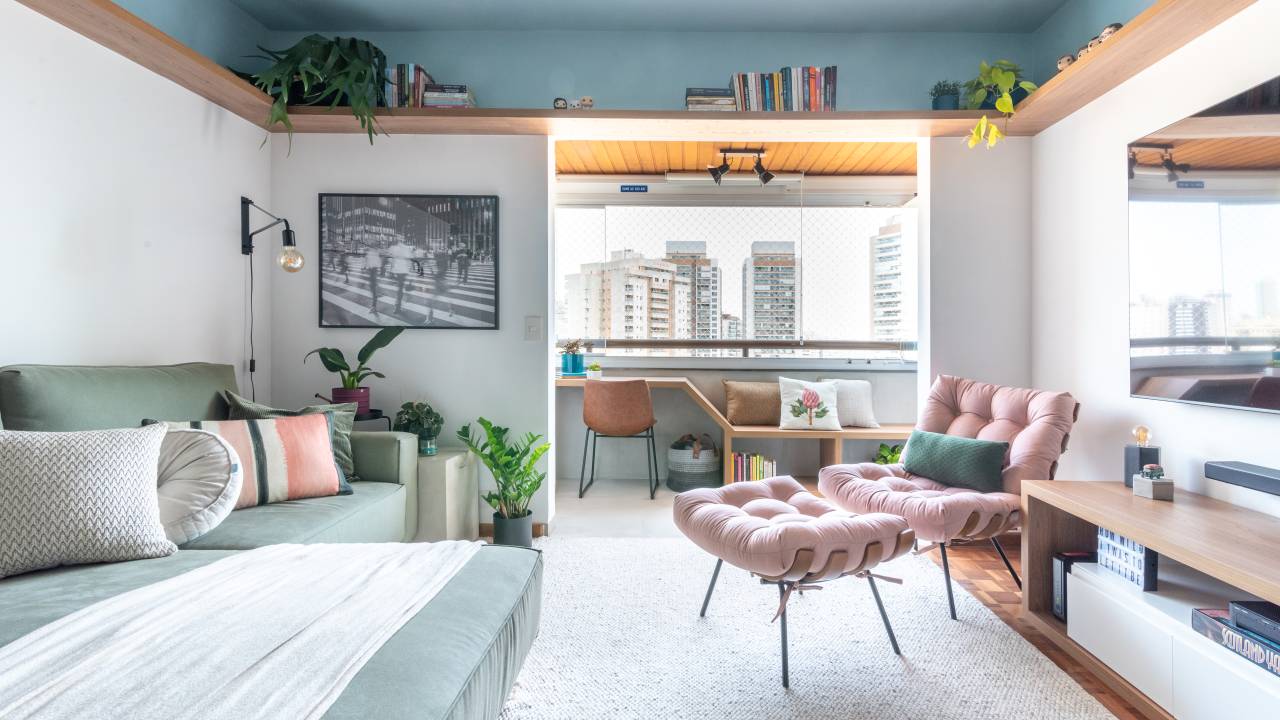Apê de 72 m² colorido e vibrante tem canto alemão e sapateira no hall rosa. Projeto de Abrazo Interiores. Na foto, sala, tapete branco, sofá verde, poltrona rosa com pufe.