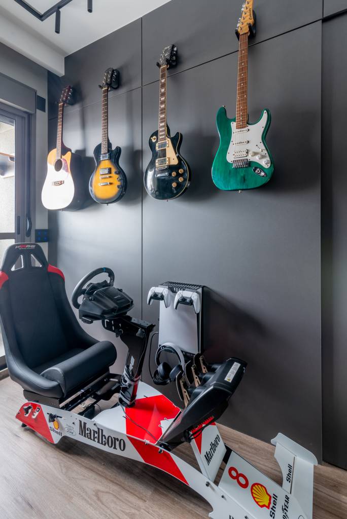 Apê de 79 m² tem mesa suspensa na sala de jantar e toalheiro elétrico no banheiro. Projeto de Red Square Arquitetura. Na foto, home office com simulador de F1 e guitarras.