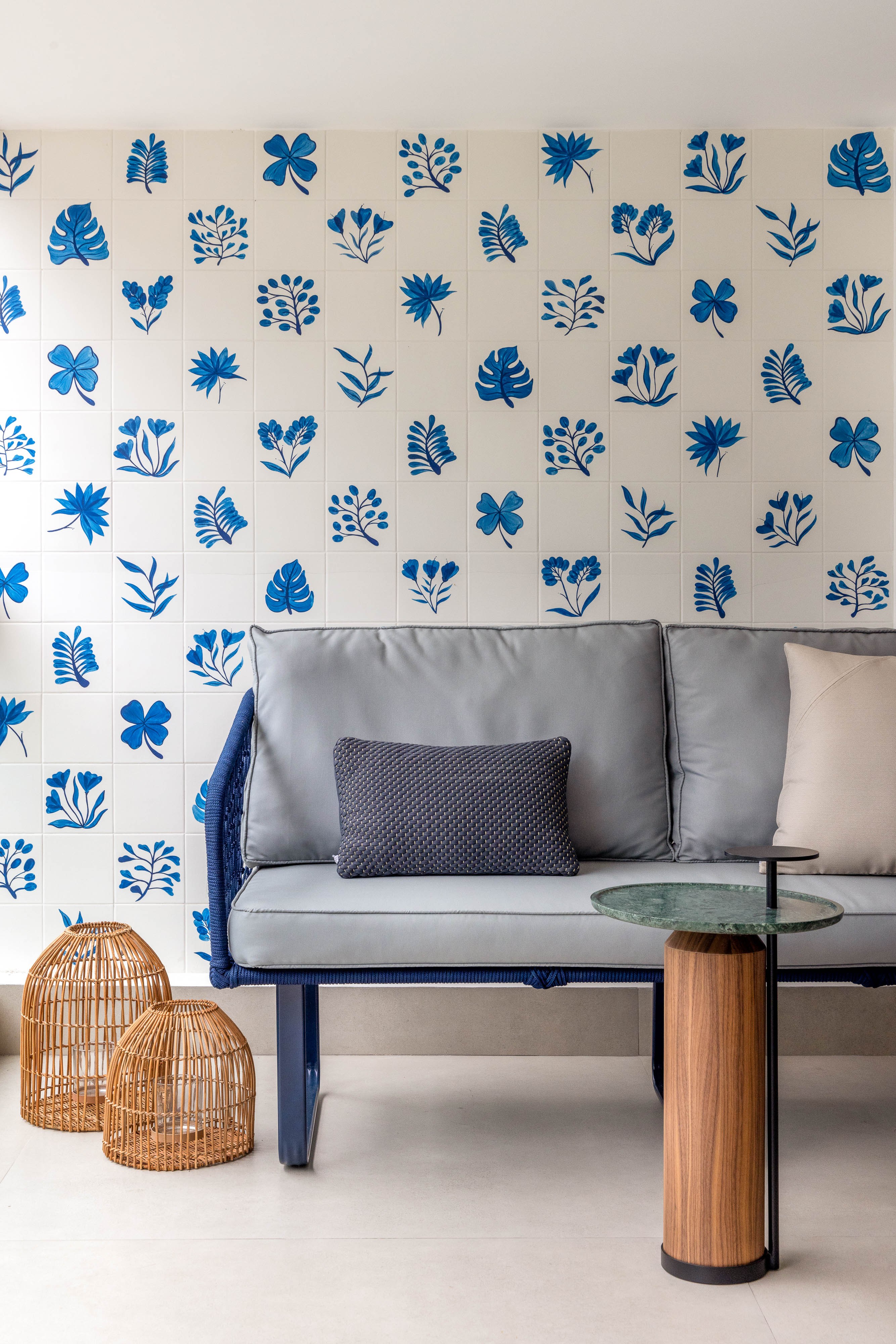 Azulejos pintados à mão com estampas botânicas revestem varanda de apê. Projeto de Renata Lemos. Na foto, varanda, sofá cinza.