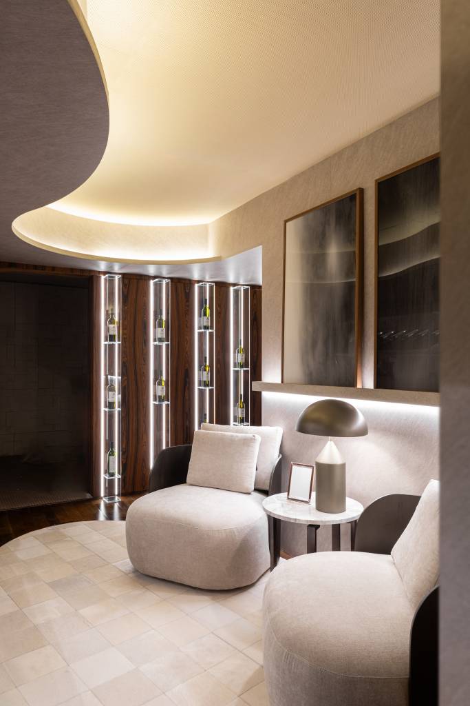 CASACOR Paraná: espaço exclusivo celebra o vinho com adega residencial. Projeto de Janaina Marques e Camila Kubota. Na foto, adega residencial com poltronas aconchegantes e mesa de apoio com luminária