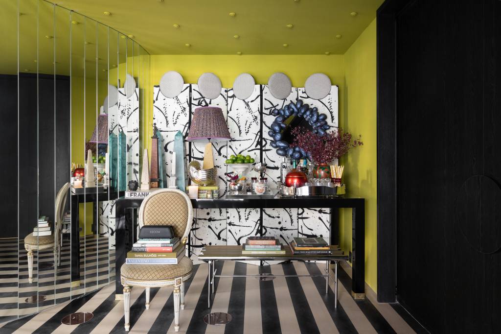 CASACOR São Paulo: hall maximalista tem parede espelhada e piso listrado. Projeto de Gustavo Scaramella. Na foto, piso listrado e aparador com objetos decorativos