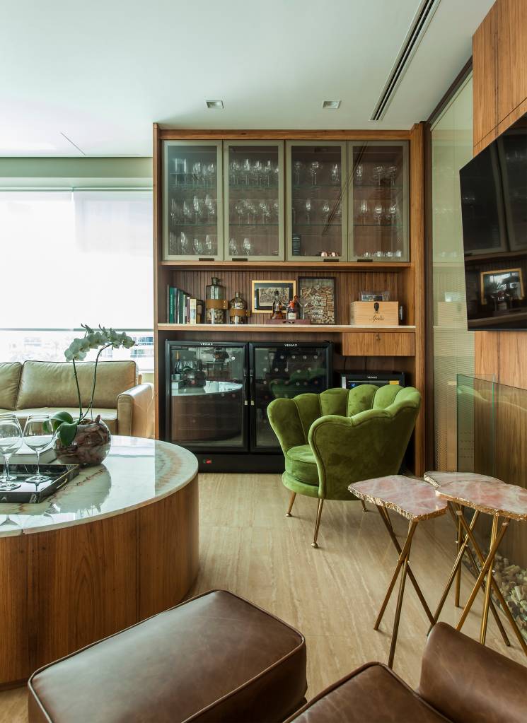 Cores naturais: veja quais são os tons mais populares com projetos e dicas. Projeto de Korman Arquitetos. Na foto, sala de estar, cristaleira em madeira, poltrona verde.