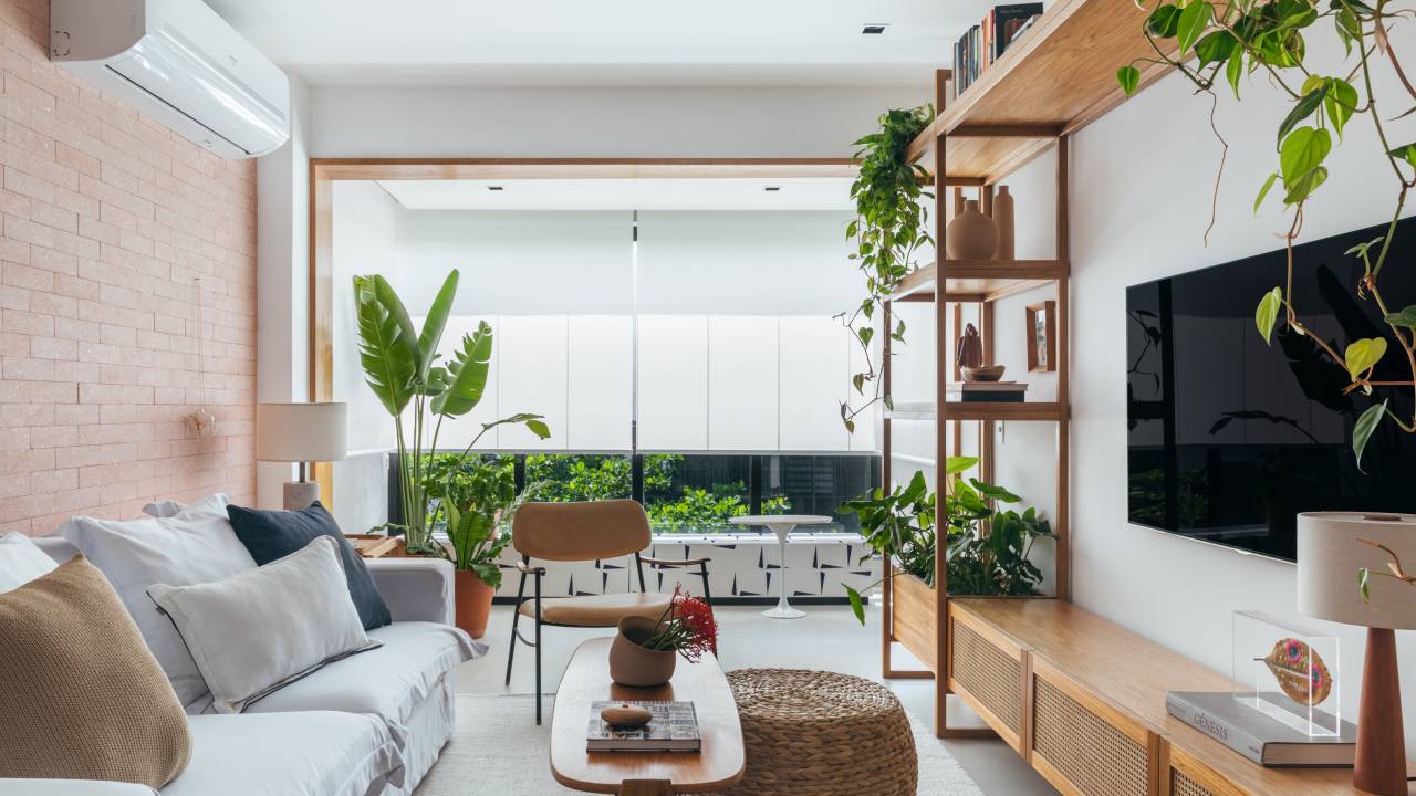 Decoração contemporânea cozy dá ar de casa para apê de 100 m². Projeto de Studio A+G. Na foto, sala de estar, plantas, marcenaria com palhinha.