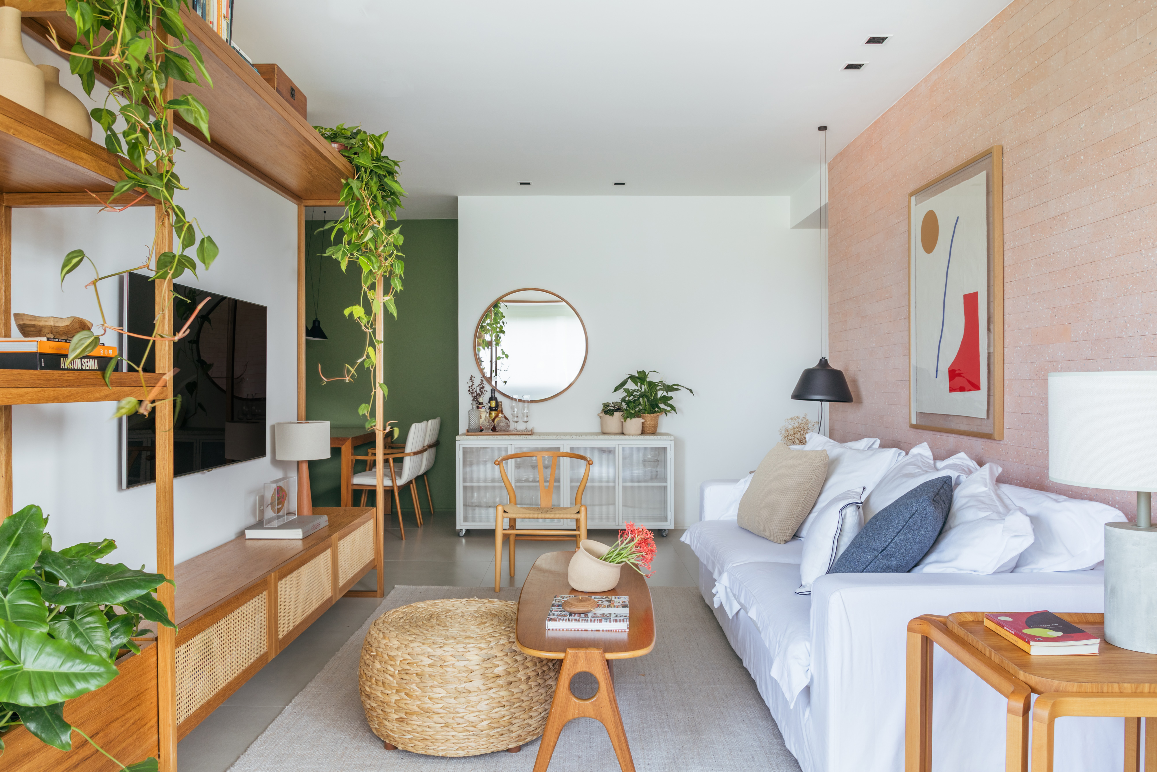 Decoração contemporânea cozy dá ar de casa para apê de 100 m². Projeto de Studio A+G. Na foto, sala de estar, espelho redondo, sofá, estante com palhinha.
