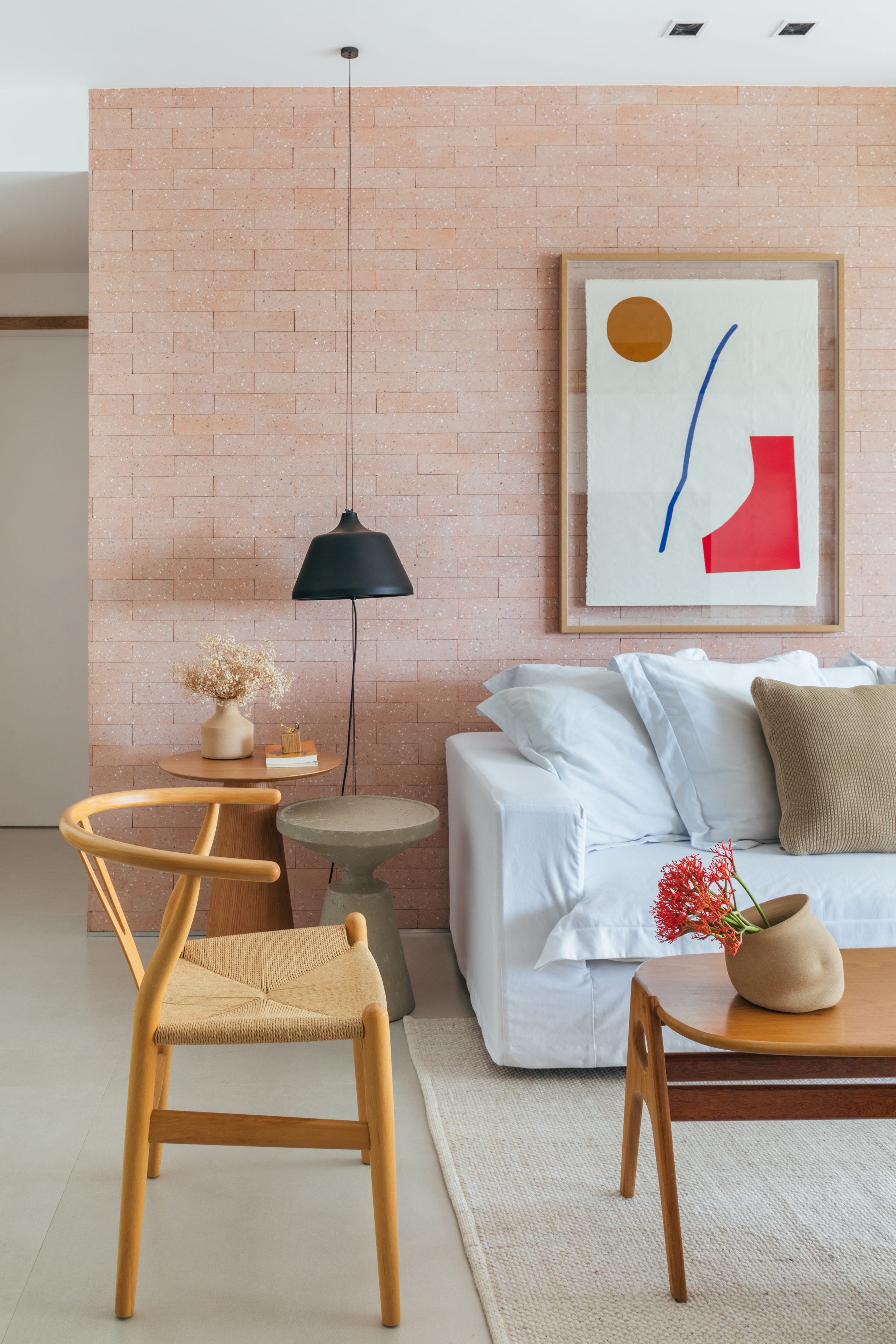 Decoração contemporânea cozy dá ar de casa para apê de 100 m². Projeto de Studio A+G. Na foto, sala de estar, parede de tijolinhos, sofá branco.