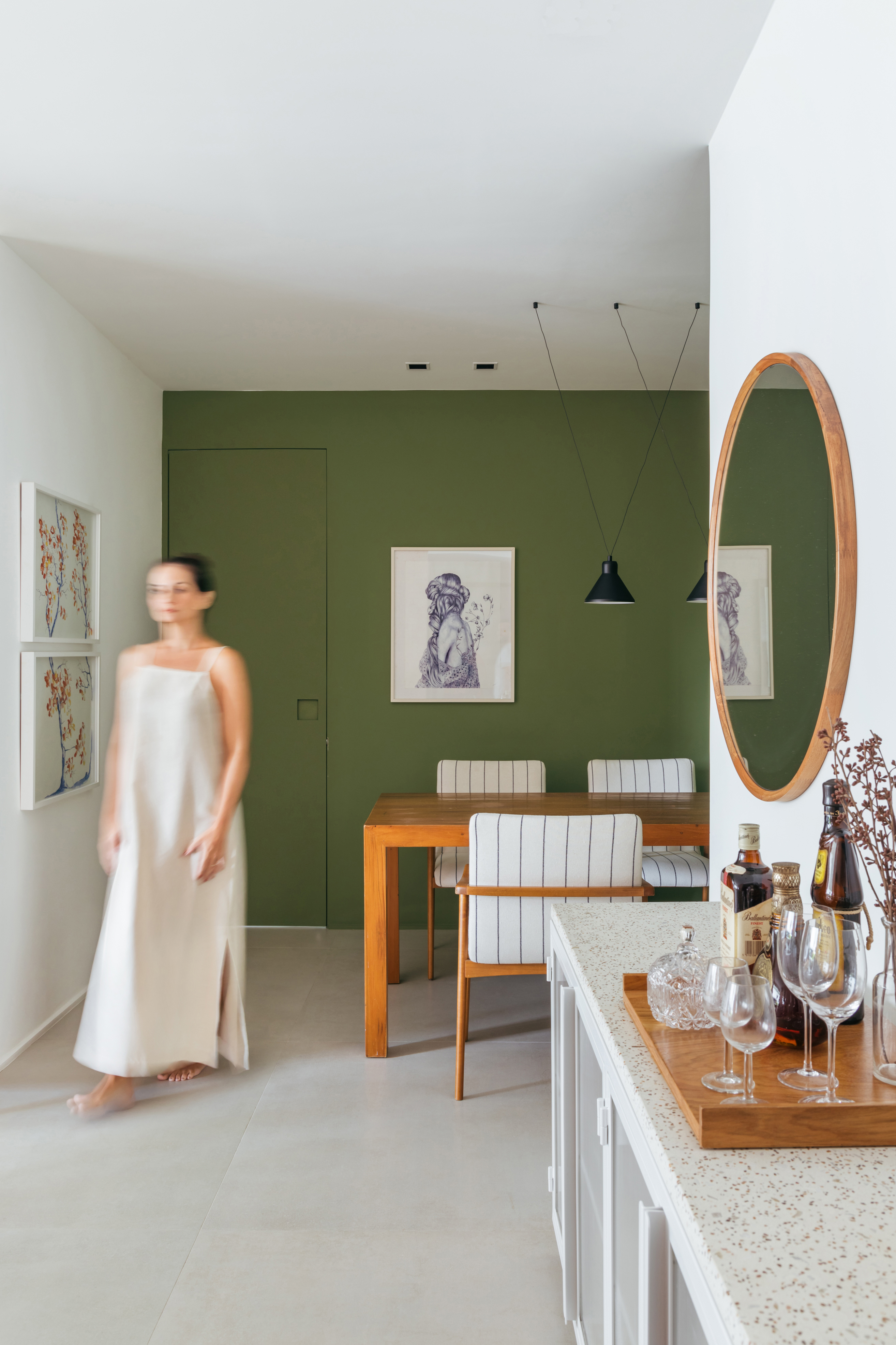 Decoração contemporânea cozy dá ar de casa para apê de 100 m². Projeto de Studio A+G. Na foto, sala de estar, parede verde, espelho redondo, sala de jantar.