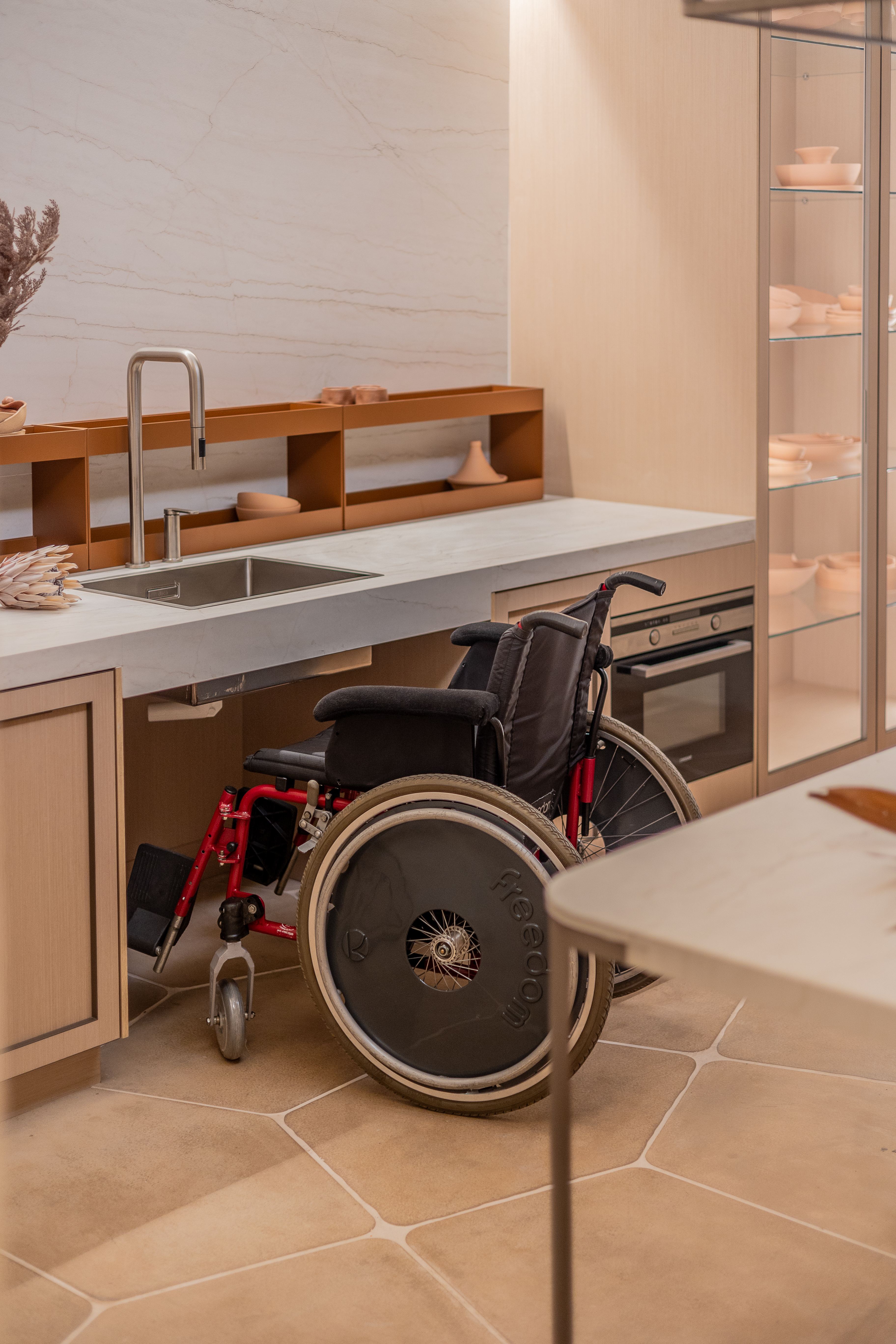 Estúdio de 88 m² traz recursos de acessibilidade de forma elegante e estética. Projeto de ADVP para a CASACOR São Paulo 2024. Na foto, cozinha, cadeira de rodas.