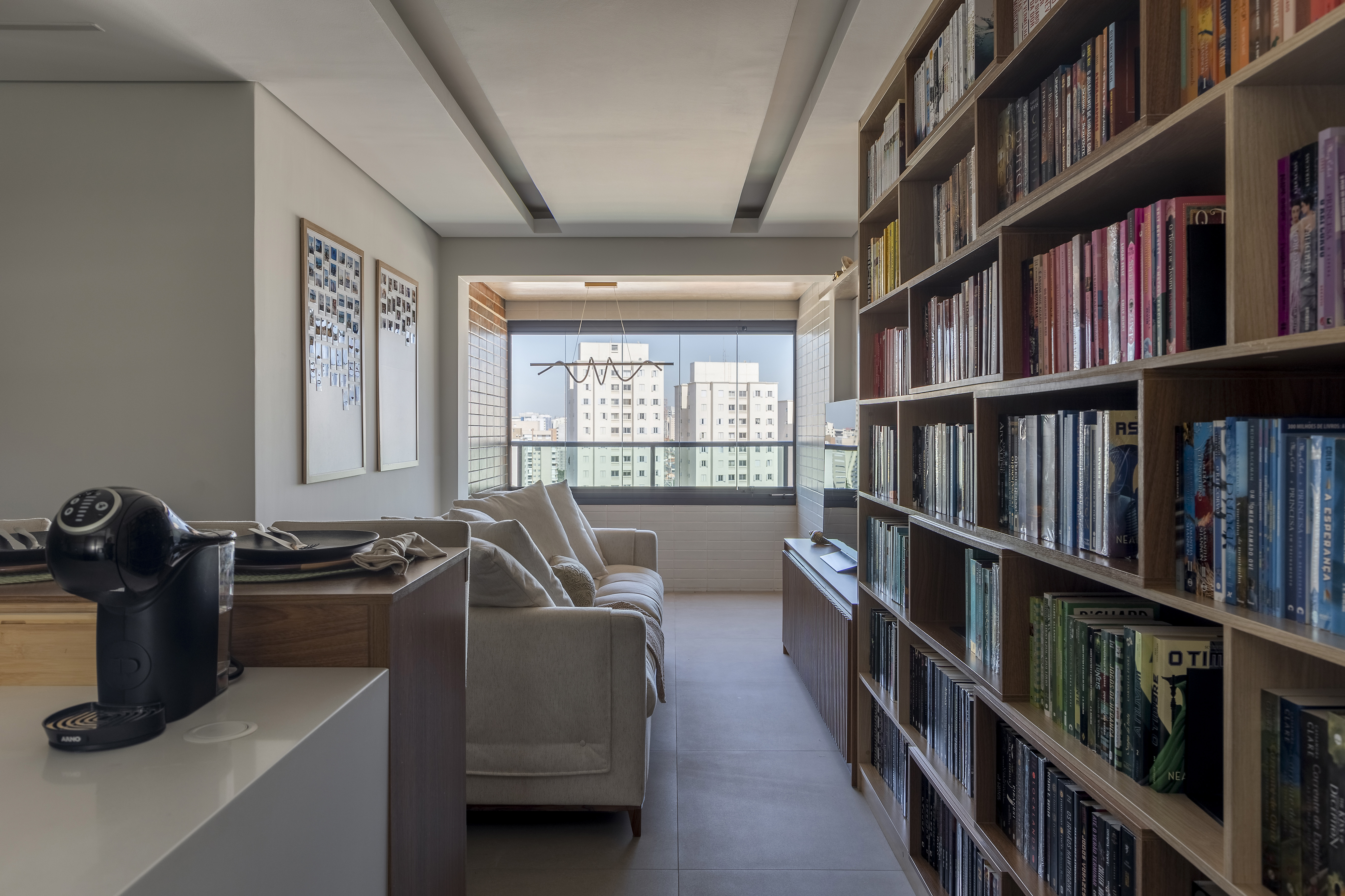 Funkos e livros ganham destaque em reforma de apê de 64 m². Projeto de Vitoria Lacerda. Na foto, sala, estante de livros organizada por cor.