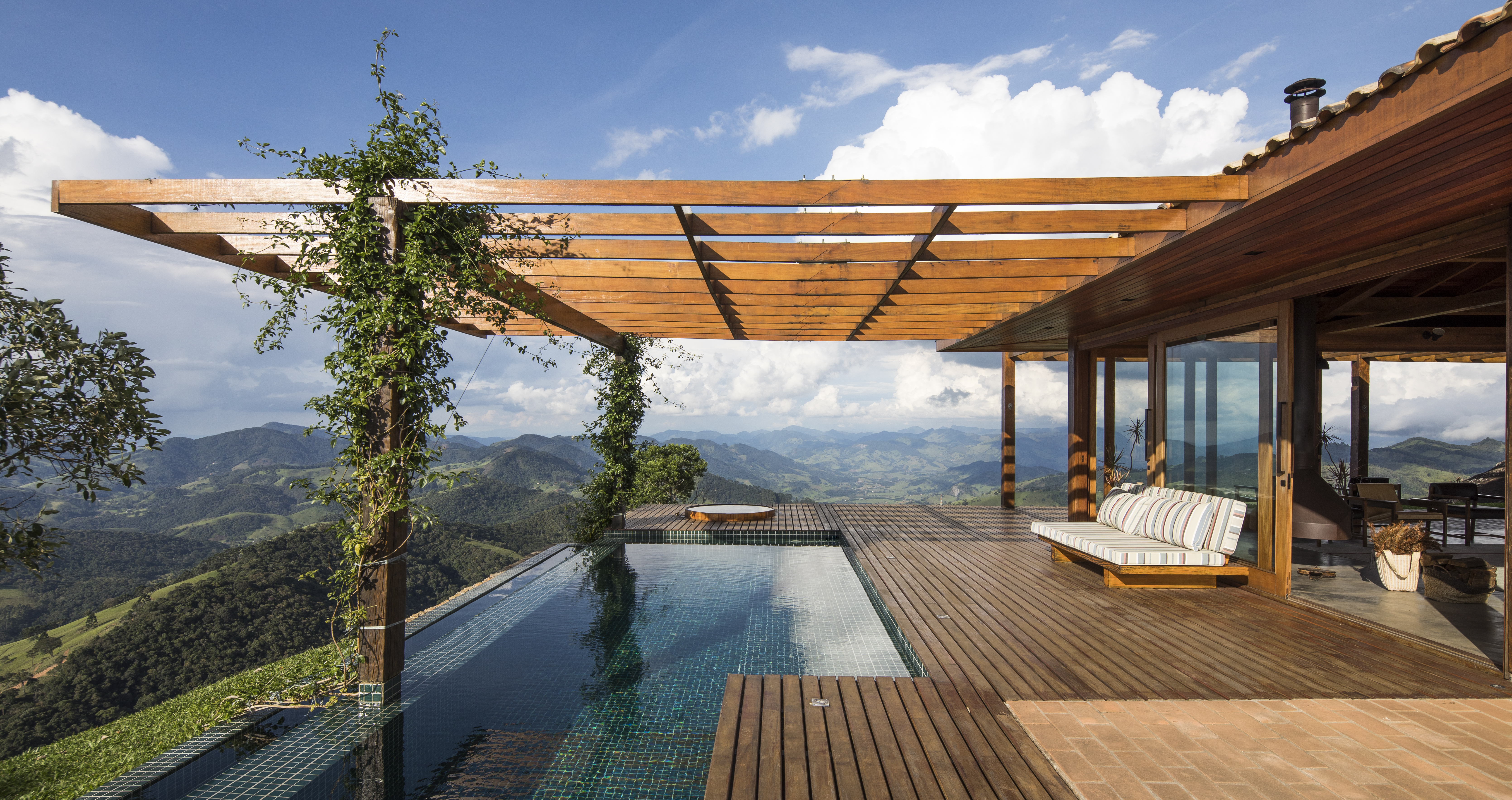 Linda casa na montanha tem lareira e cozinha rústica com fogão à lenha. Projeto de Sabella Arquitetura. Na foto, piscina, deck.