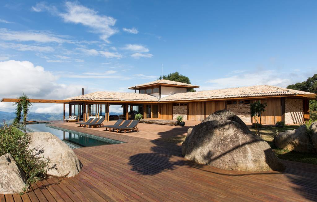 Linda casa na montanha tem lareira e cozinha rústica com fogão à lenha. Projeto de Sabella Arquitetura. Na foto, área externa, deck.