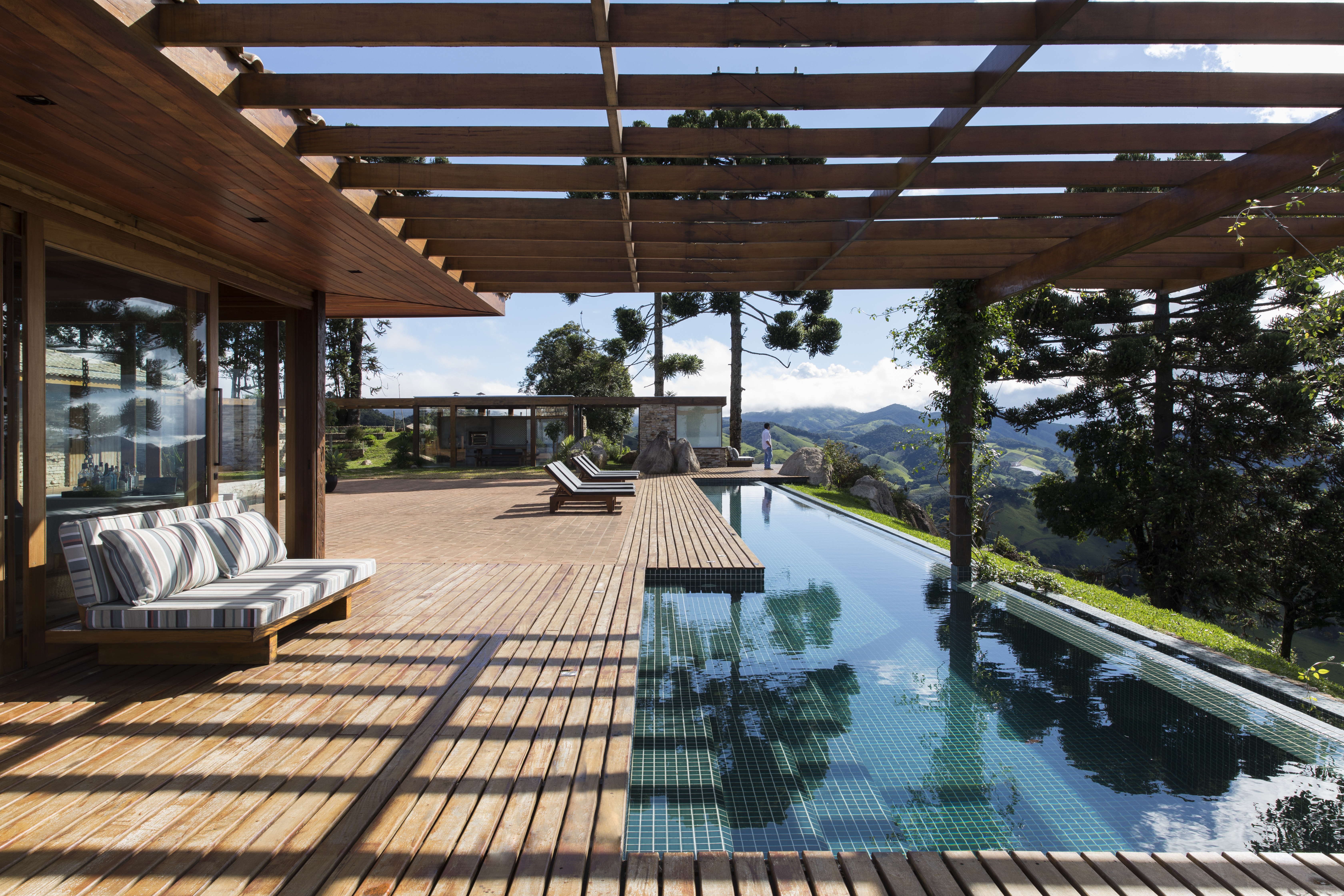 Linda casa na montanha tem lareira e cozinha rústica com fogão à lenha. Projeto de Sabella Arquitetura. Na foto, piscina, deck.