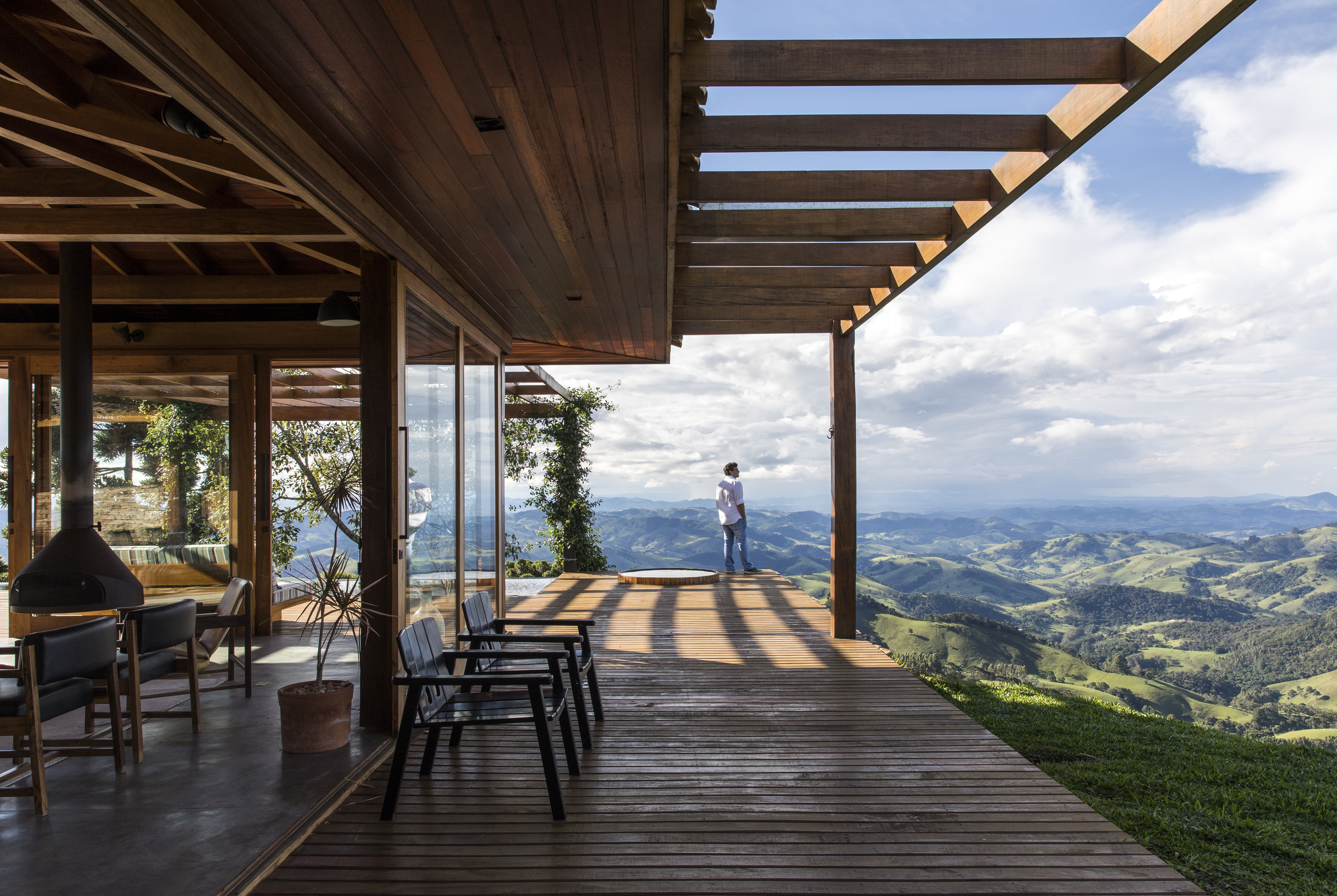 Linda casa na montanha tem lareira e cozinha rústica com fogão à lenha. Projeto de Sabella Arquitetura. Na foto, varanda, deck, vista.