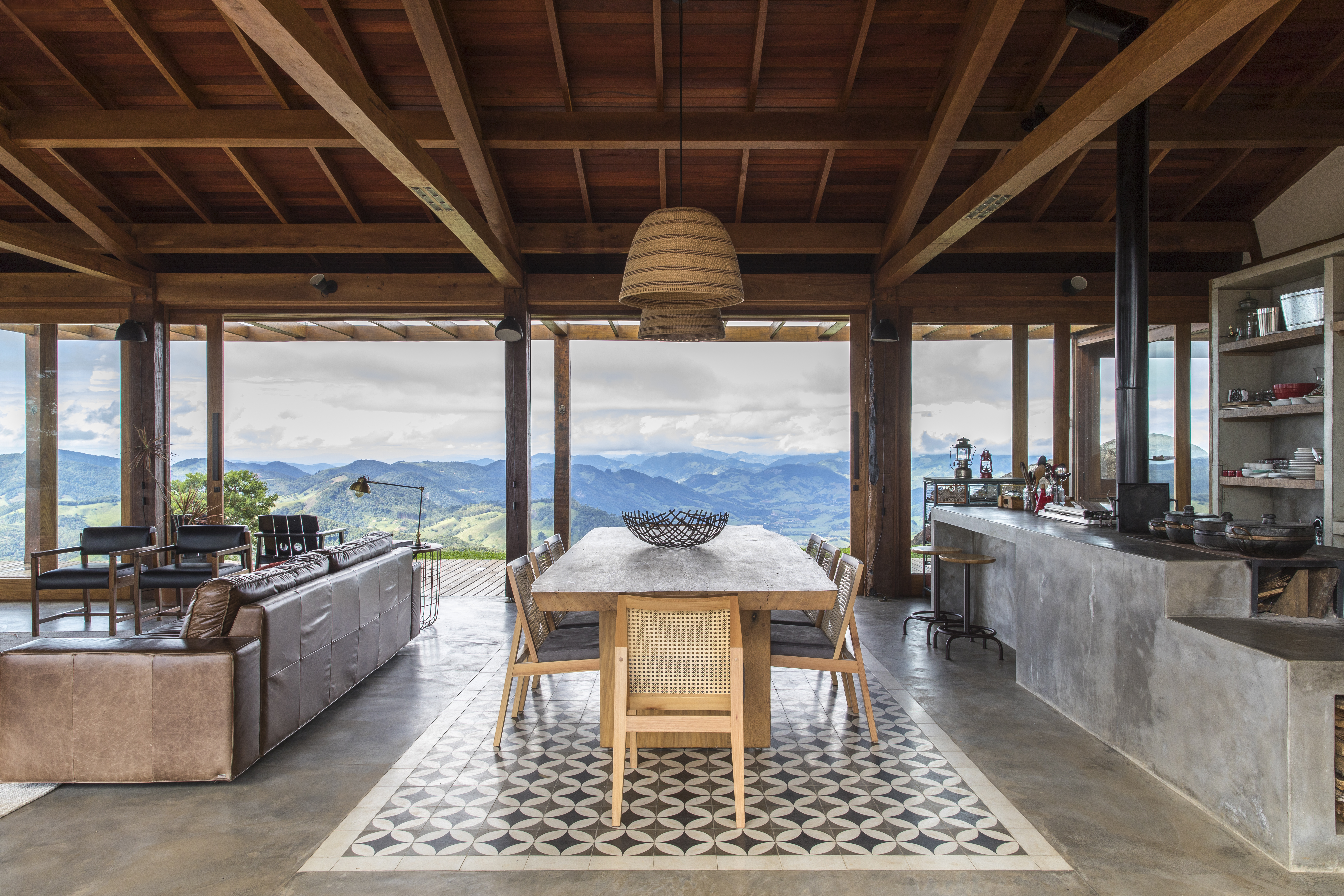 Linda casa na montanha tem lareira e cozinha rústica com fogão à lenha. Projeto de Sabella Arquitetura. Na foto, cozinha integrada, tapete de ladrilhos.