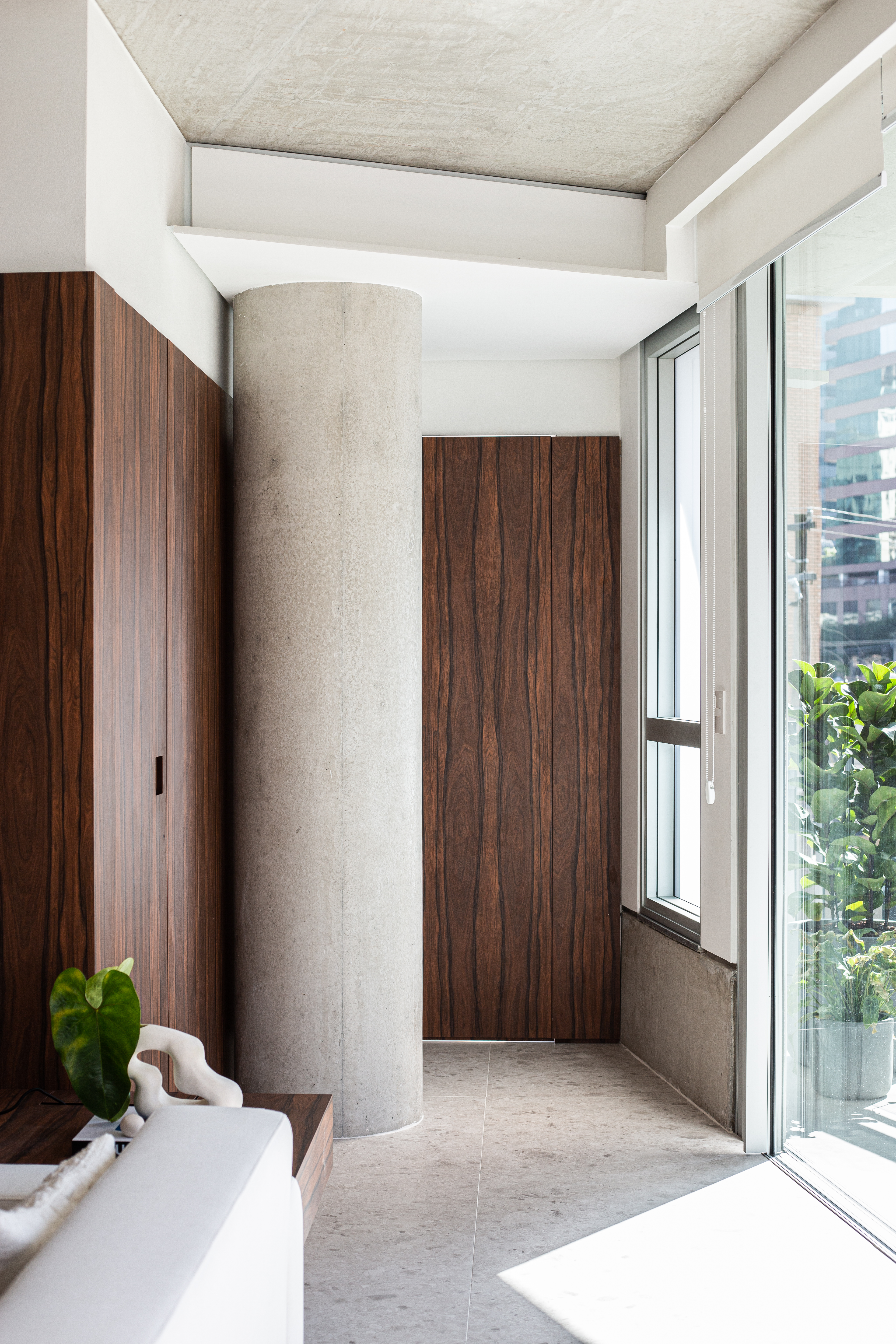 Painéis em madeira pau ferro contrastam com laje de concreto neste apê. Projeto de Estúdio Pluri. Na foto, pilar de concreto.
