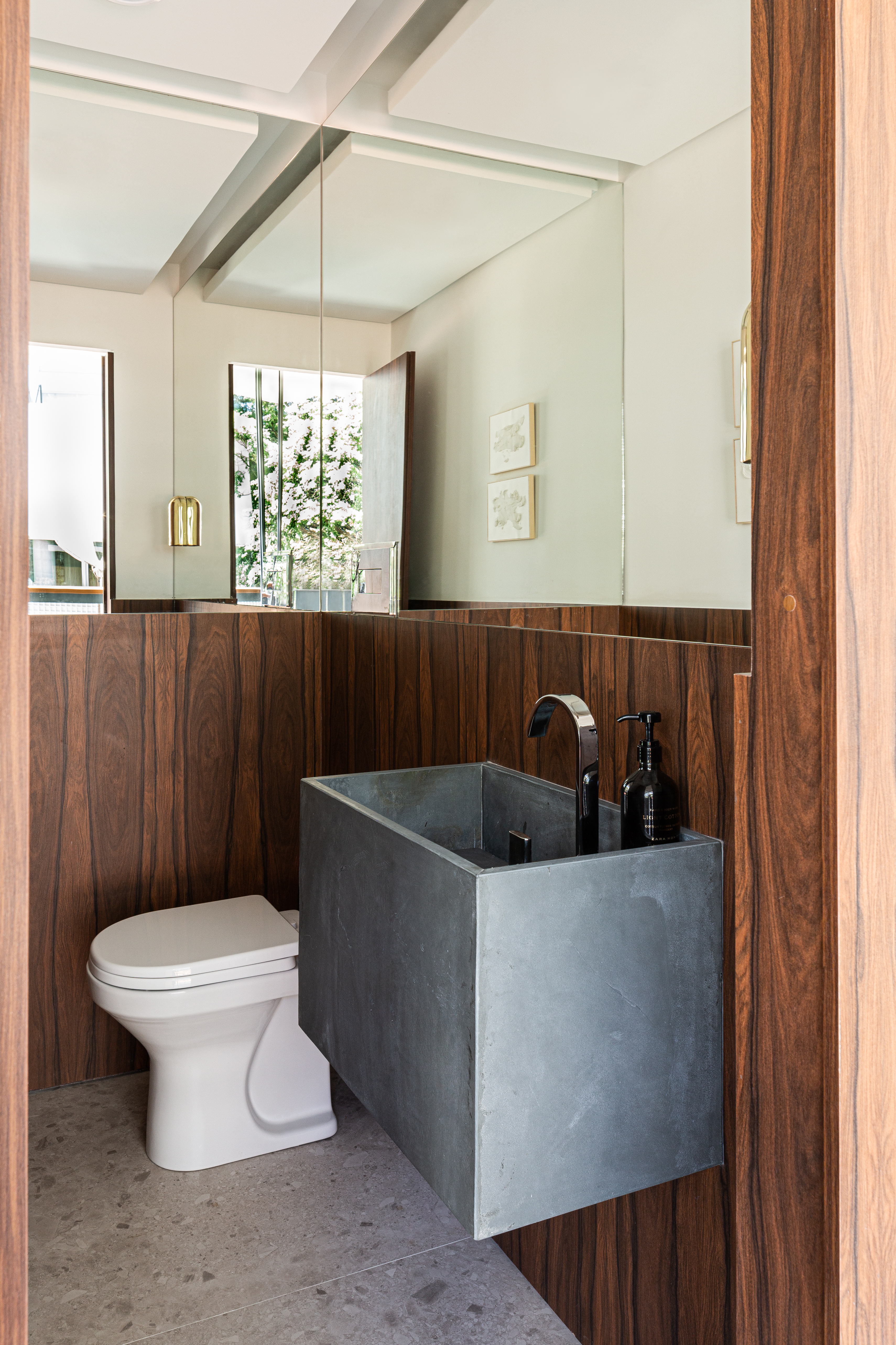 Painéis em madeira pau ferro contrastam com laje de concreto neste apê. Projeto de Estúdio Pluri. Na foto, banheiro pequeno com cuba esculpida.