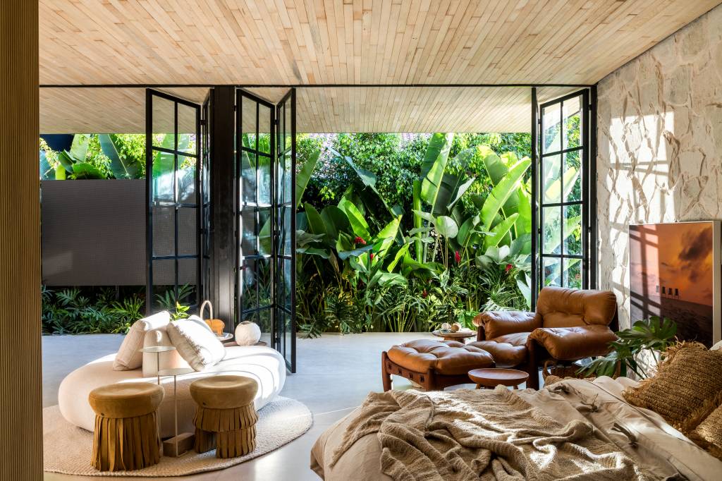 Pedras e vegetação em abundância marcam a estética orgânica deste loft. Projeto de Maria Alice Crippa e Gustavo Assis. Na foto, suíte com janela alta e jardim vertical