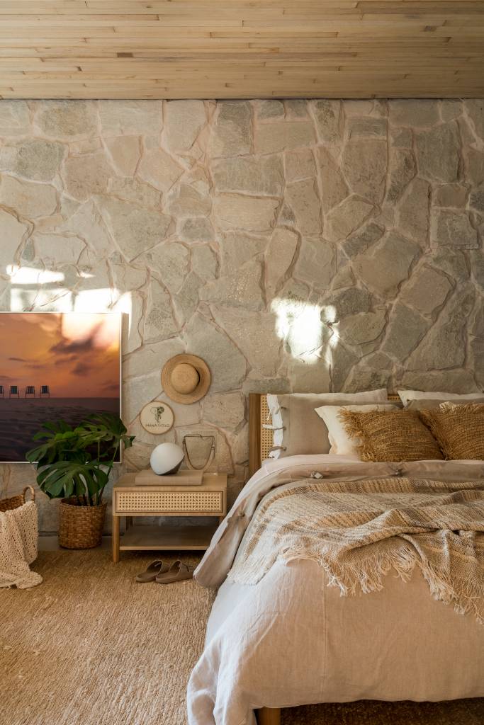 Pedras e vegetação em abundância marcam a estética orgânica deste loft. Projeto de Maria Alice Crippa e Gustavo Assis. Na foto, suíte com parede de pedra