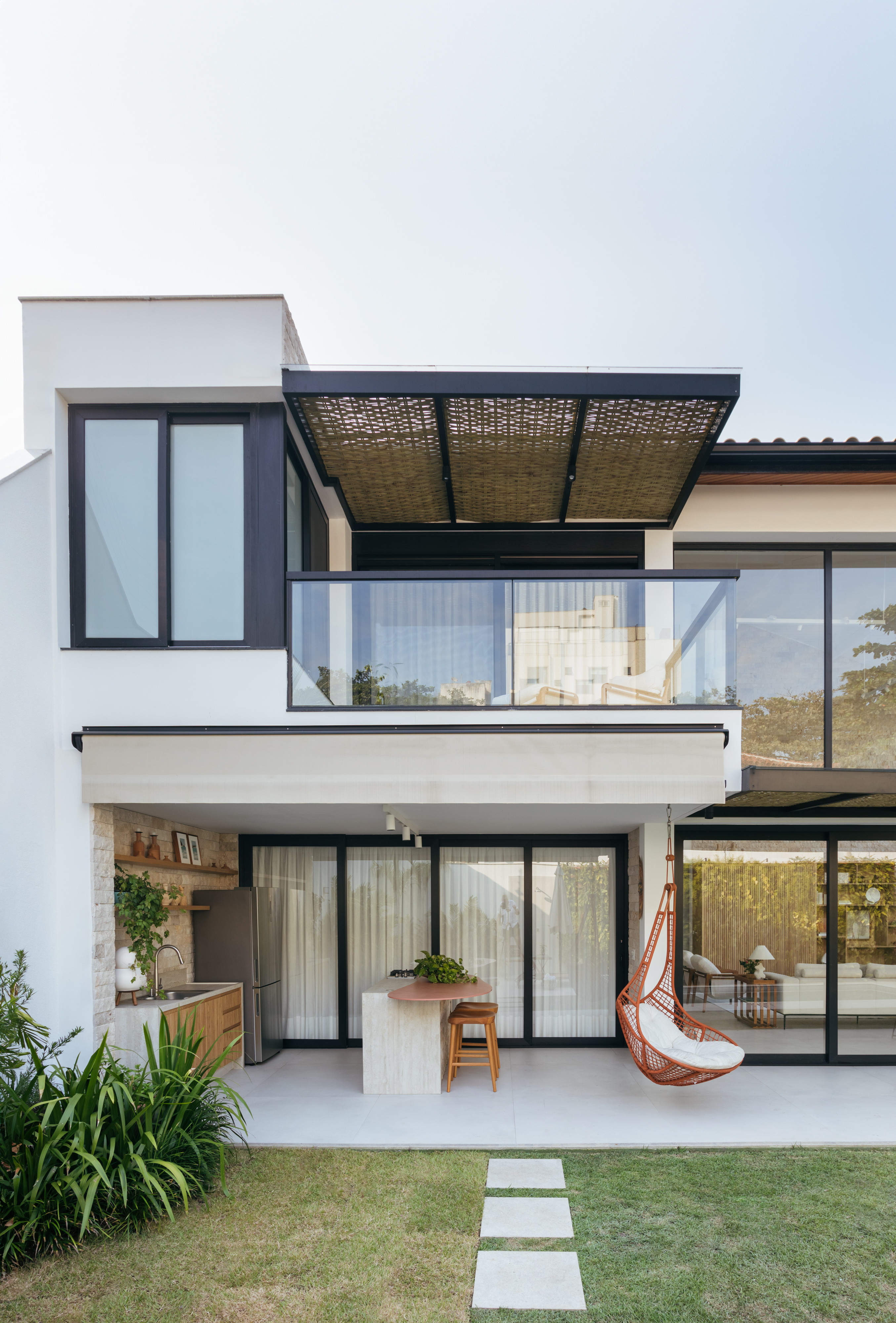 Pergolados com forro em fibras de bambu trançadas envolvem casa de 195 m². Projeto de Amanda Miranda. Na foto, fachada.