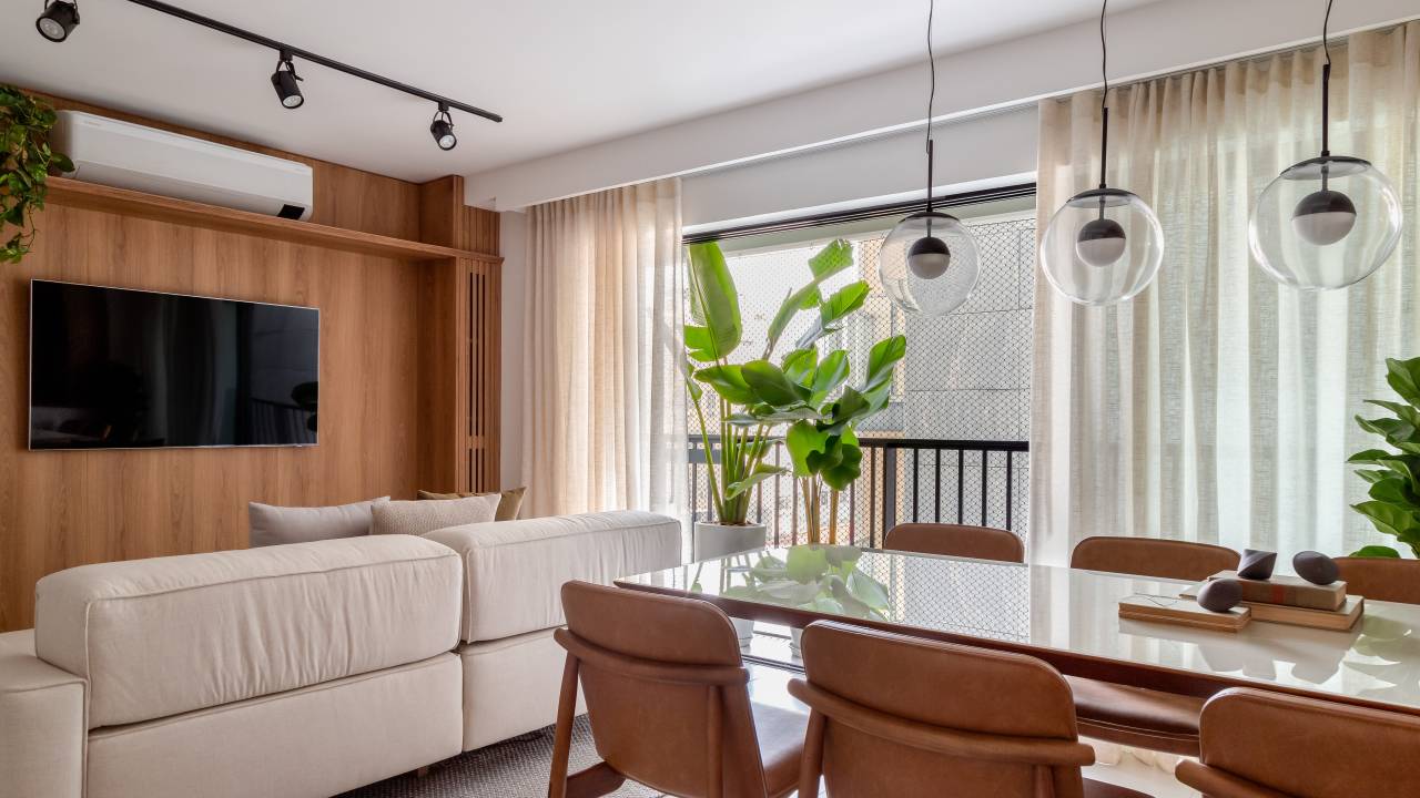 Reforma em apê de 73 m² cria mini lavabo com paredes de drywall. Projeto de Casa Tauari. Na foto, sala de estar integrada com jantar, painel de madeira com tv.