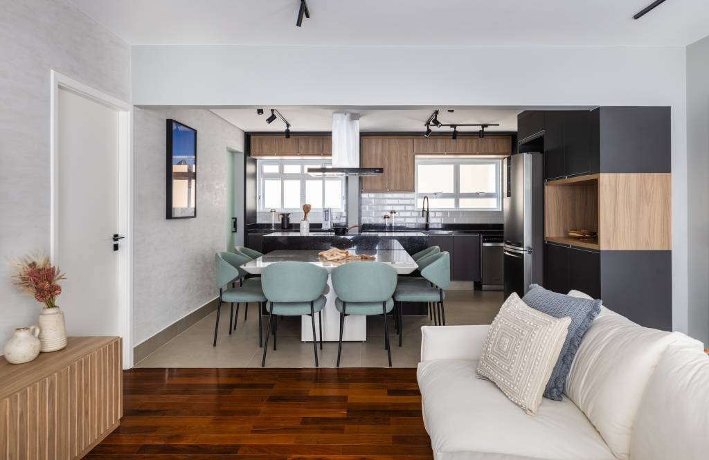 Apê tem cozinha com marcenaria preta e home office com painel ripado branco. Projeto de Duno Arquitetura. Na foto, cozinha integrada, mesa de jantar.