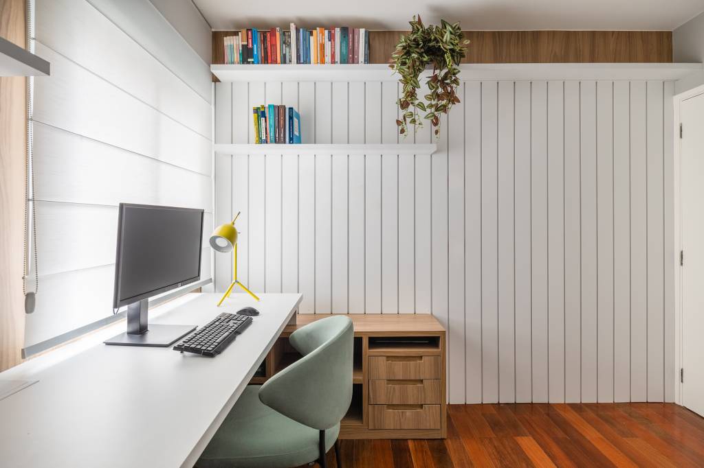 Apê tem cozinha com marcenaria preta e home office com painel ripado branco. Projeto de Duno Arquitetura. Na foto, home office duplo, bancada branca.