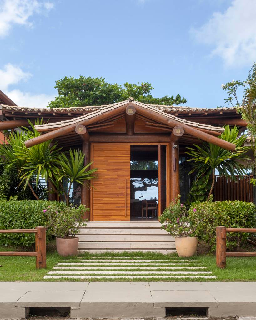 Casa de praia tem estrutura de toras de árvore e pergolados com esteiras em tala de dendê. Projeto de DB Arquitetos. Na foto, piscina, fachada.