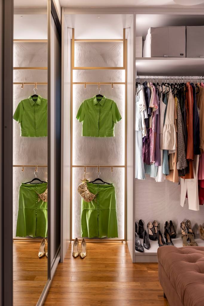 Closet sem portas e com iluminação interna é protagonista em suíte de apê. Projeto de Spaço Interior. Na foto, guarda roupa aberto iluminado.