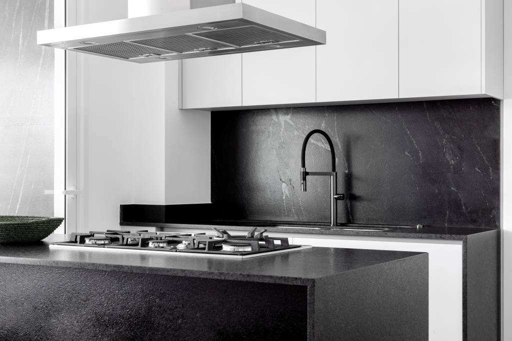 Cozinha elegante de apê de 275 m² tem bancada com tampos de granito preto