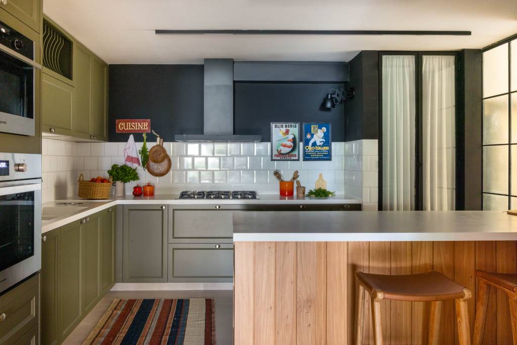 Cozinha de apê tem armário verde oliva, azulejo branco e paredes com toque preto
