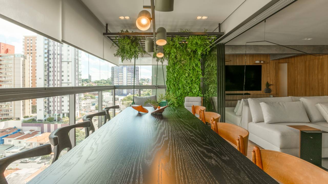 Estrutura em serralheria preta abriga jardim vertical e balanço em varanda de apê. Projeto de Rosana Pintor Arquitetura e Interiores. Na foto, mesa de madeira escura.