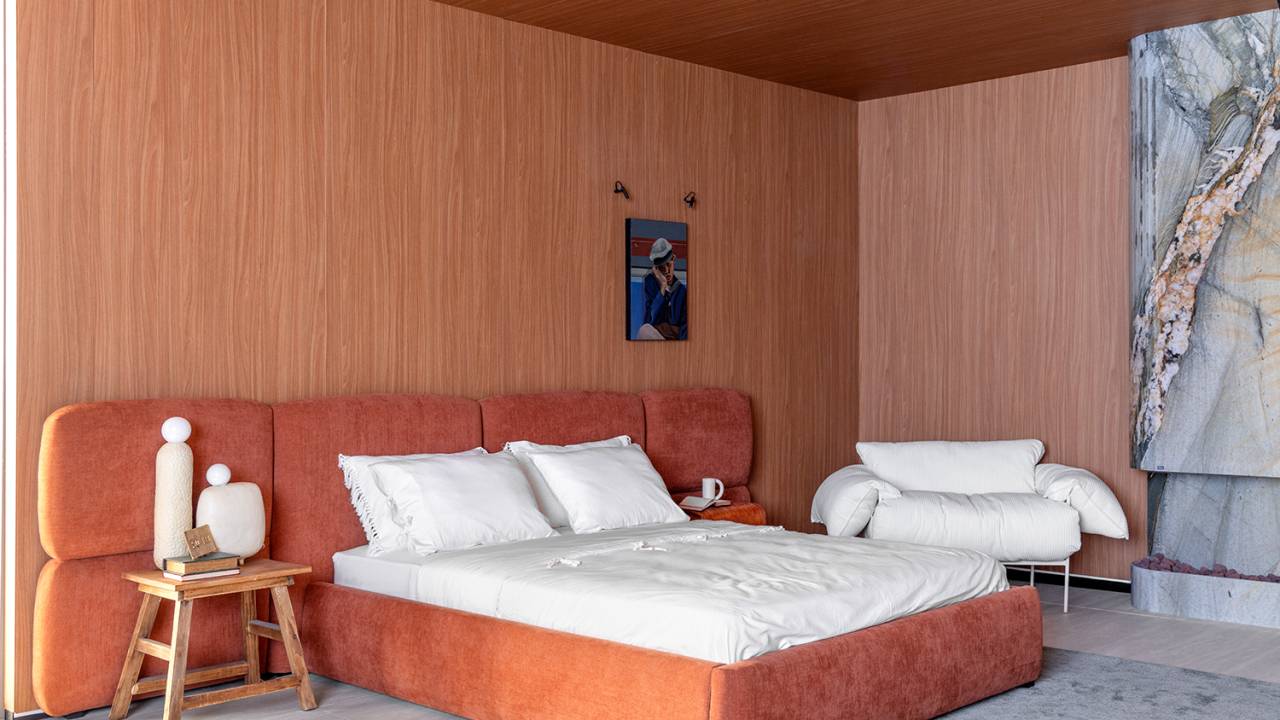 Loft de 83 m² pensado para o acolhimento tem cama e sofás exclusivos. Projeto de Daniela Schmitt para a CASACOR SC 2024. Na foto, quarto em tons terrosos, cabeceira estofada.