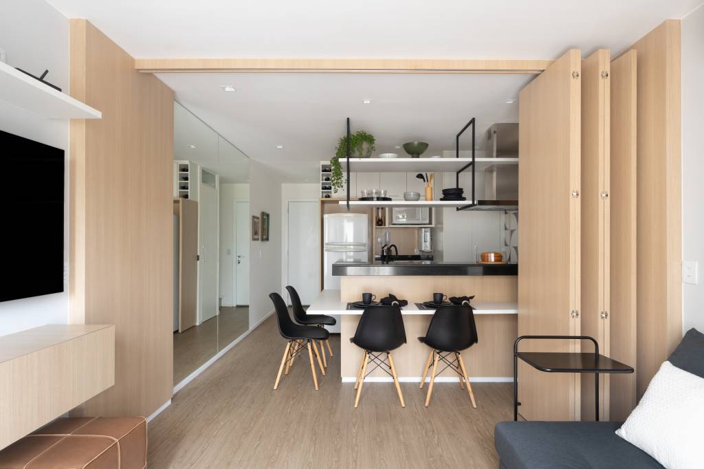 Painéis articulados de madeira separam a cozinha da sala de estar, que pode ser quarto