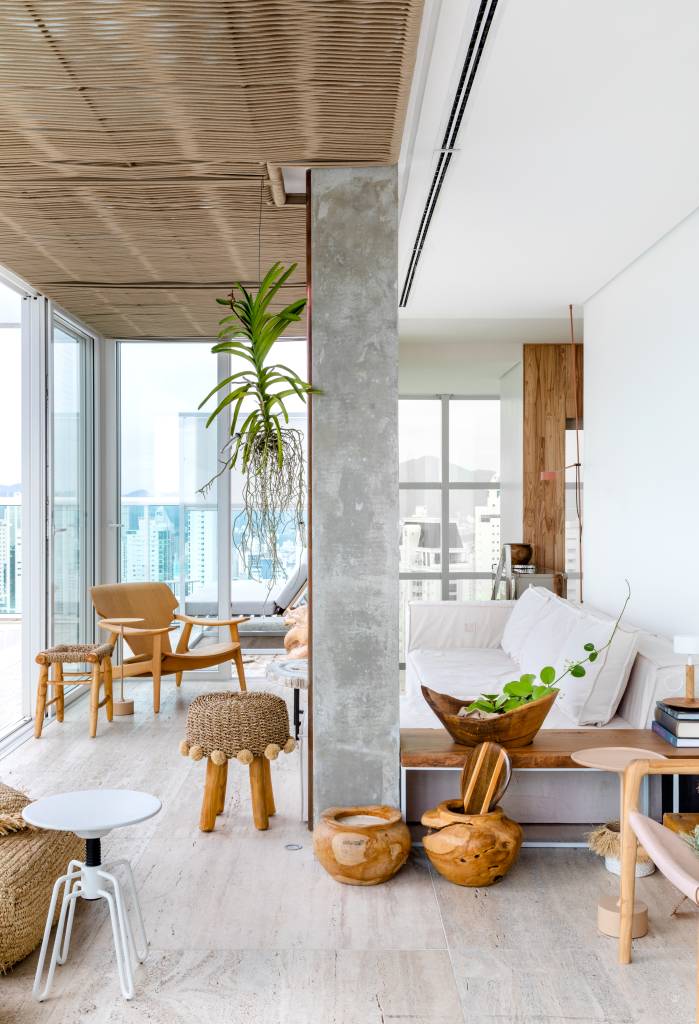 Conjunto de cadeiras diferentes na mesa de jantar dá charme à área gourmet. Projeto de Simara Mello. Na foto, sala, pilar de concreto, cadeira de madeira.