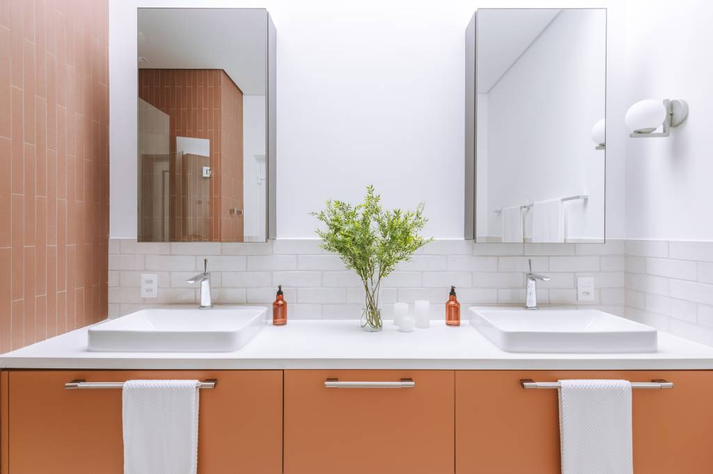 Cozinha azul e beliche em color block são destaque em casa de praia. Projeto de Rawi Arquitetura + Design. Na foto, banheiro no tom terracota.