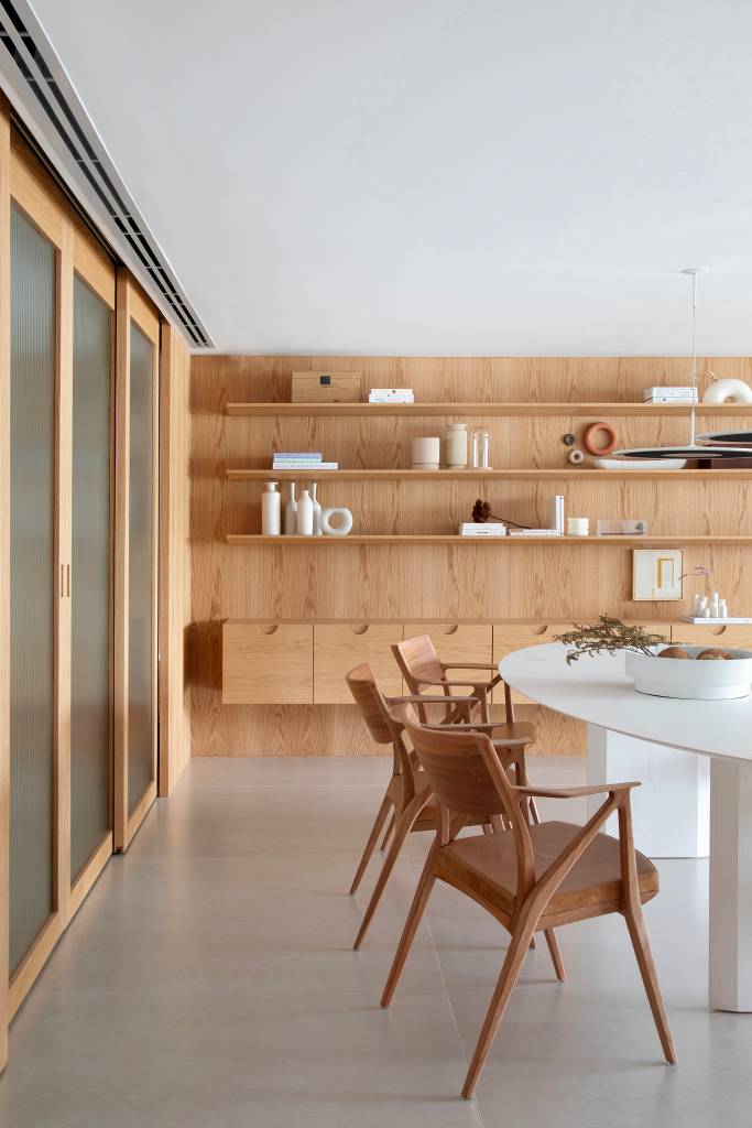 Escada de serralheria branca leva a mezanino com sala de TV e home office em apê. Projeto de Natália Lemos. Na foto, sala de jantar, mesa branca.