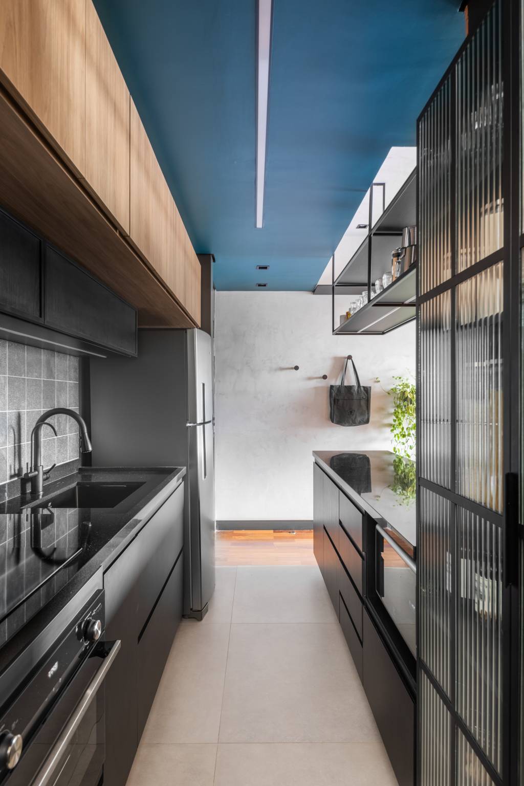 industrial-e-leve-apartamento-combina-serralheria-cores-claras-escuras-studio-ela-01-cozinha-preta-azul Industrial e leve: apartamento combina serralheria com cores claras e escuras. Projeto de Studio Elã. Na foto, cozinha integrada, teto azul, marcenaria preta.