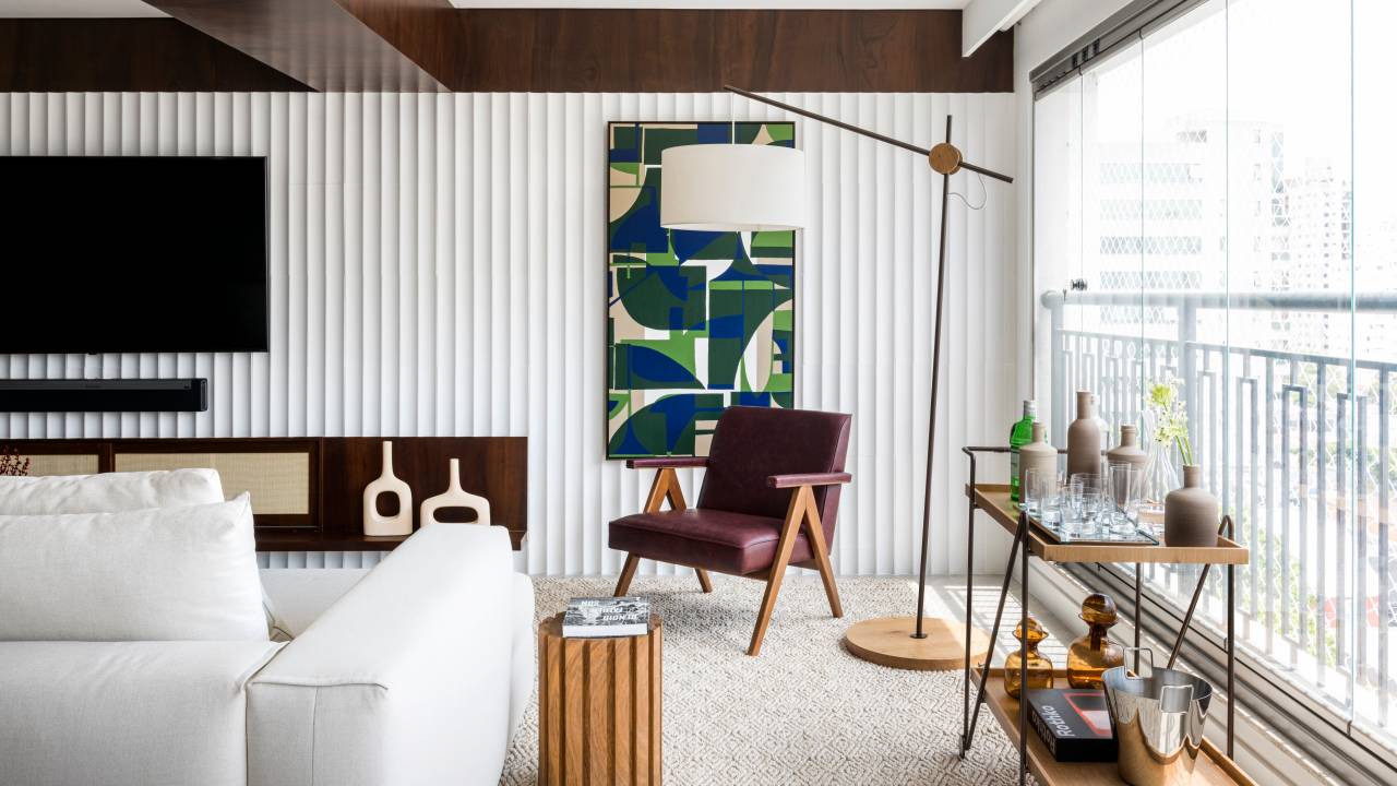 Madeira imbuia e pedra Calacatta criam estilo Mid-Century neste apartamento. Projeto de Vivi Cirello. Na foto, sala, poltrona roxa, ripado branco.