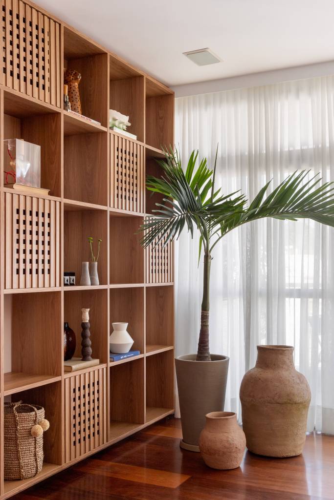 Materiais e acabamentos resistentes foram a escolha para apê lar de 4 gatinhos e cão. Projeto de Casa Tauari. Na foto, sala, palmeira, estante de nichos piso-teto.