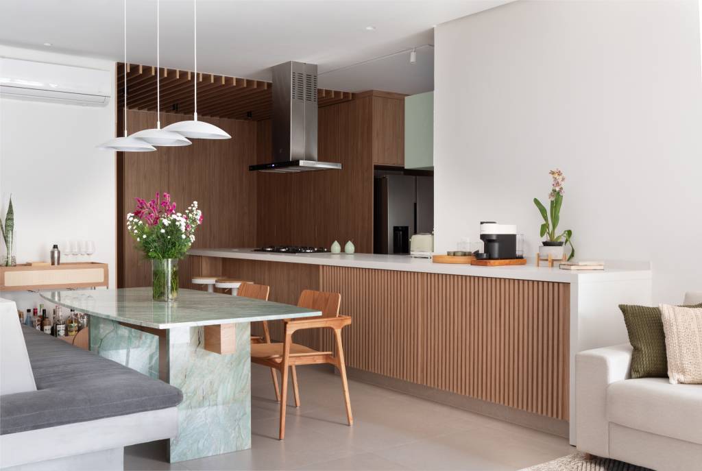 Pergolado com forro de bambu cria área de apoio charmosa para cozinha gourmet. Projeto de House in Rio Arquitetura. Na foto, sala de jantar com mesa de quartzito verde.