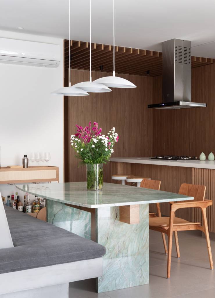 Pergolado com forro de bambu cria área de apoio charmosa para cozinha gourmet. Projeto de House in Rio Arquitetura. Na foto, sala de jantar com mesa de quartzito verde.