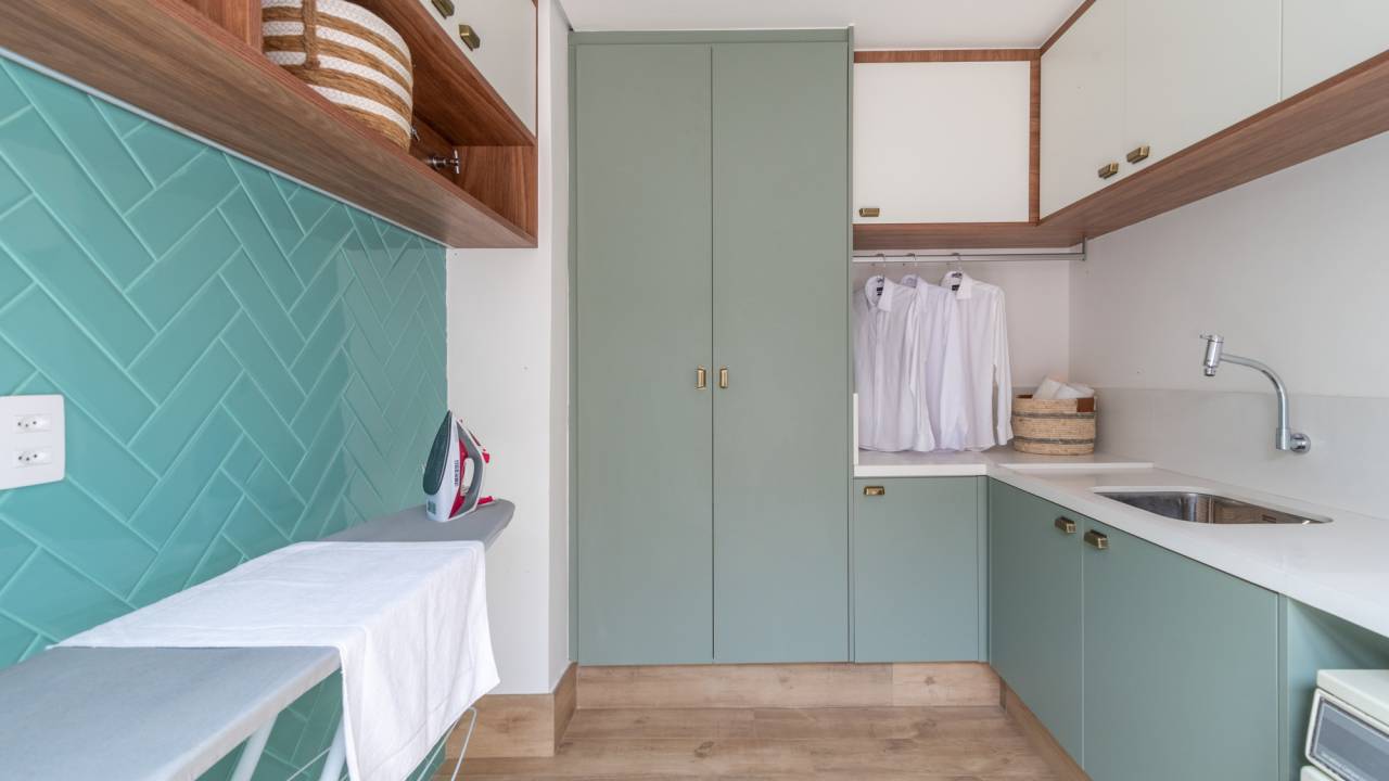 6 pontos que devem ser considerados para uma lavanderia prática e organizada. Projeto de Isabella Nalon. Na foto, área de serviço, tábua de passar roupa, parede de azulejos azuis.