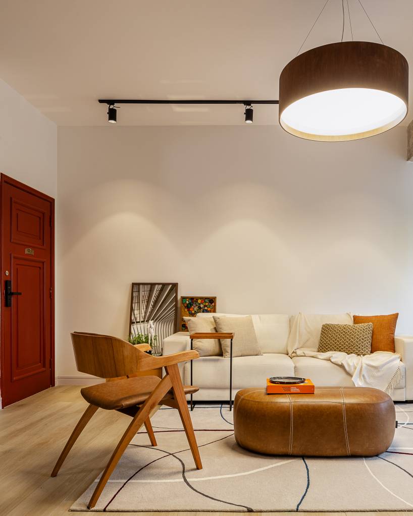 Portas vermelhas trazem toque de cor à apê sóbrio e clean de 120 m². Projeto de Studio MEMM. Na foto, sala de estar, luminária, sofá branco.