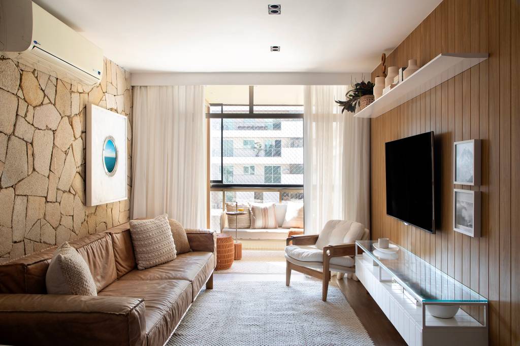 Tapete com trama artesanal, cortinas de linho e parede de pedras compõem apê de 120 m²