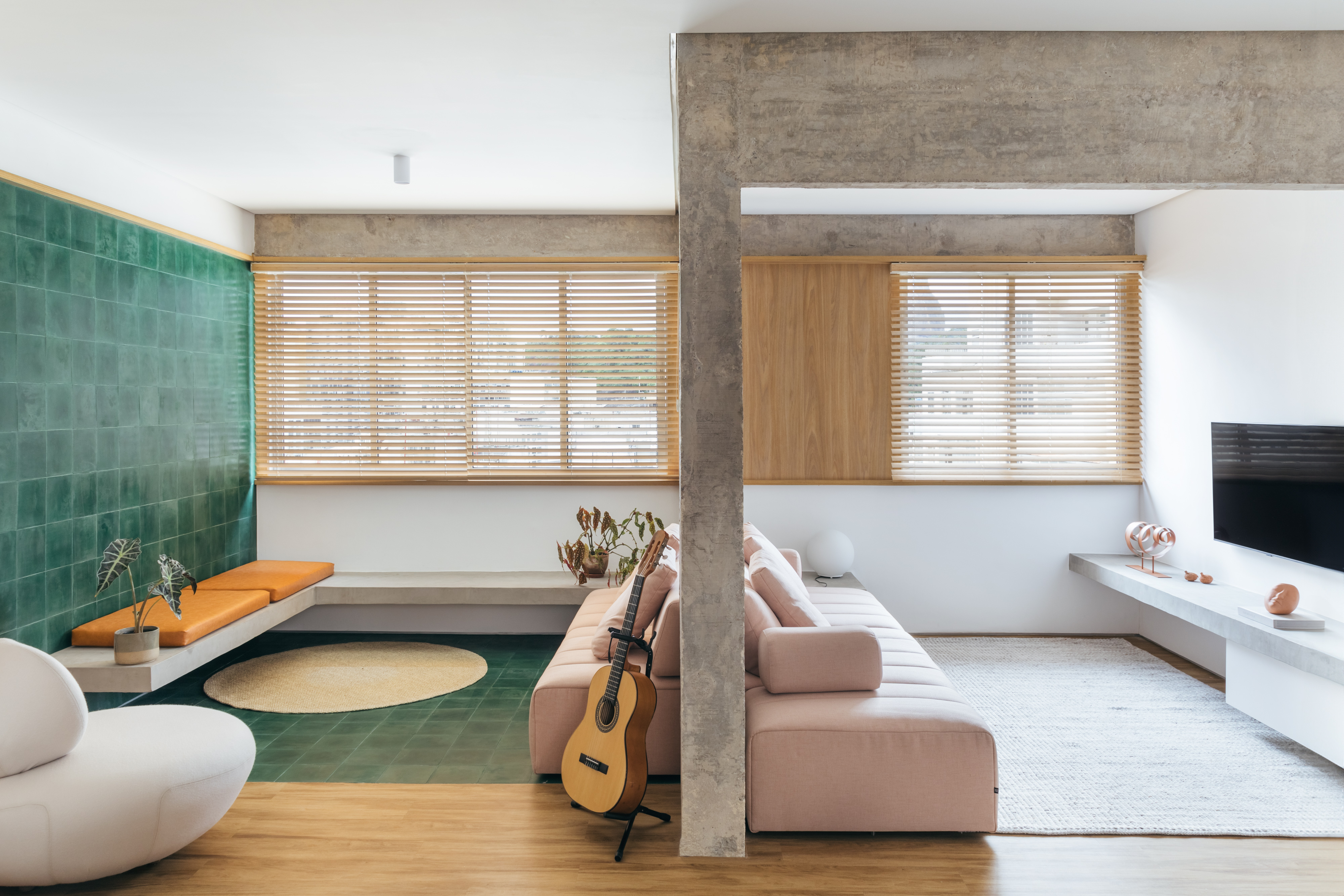 Sala de estar é ampliada com integração ao quarto, de OCCA+ Arquitetura. Na foto, sofá rosa no centro da sala.